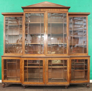 A Georgian mahogany breakfront library bookcase, the shaped pediment above triple bookcase enclosed by glazed panelled doors, the interior fitted adjustable shelves, the base fitted shelves enclosed by astragal glazed panelled doors, raised on turned supports 84"h x 97"w x 23 1/2"
