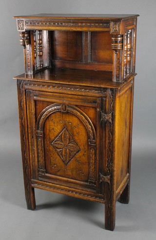 A Victorian carved oak cabinet, the upper section with open recess, the base fitted a cupboard enclosed by an arched panelled door, labelled to the reverse W Charles Tozer of 26 Brook Street, London, 53"h x 28"w x 15"d 