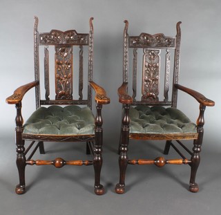A pair of Art Nouveau carved oak stick and bar back carver chairs with upholstered seats raised on club supports 