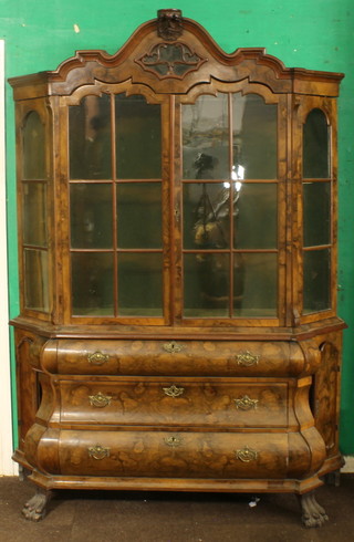 An 18th/19th Century Dutch cabinet, the shaped upper section fitted shelves enclosed by glazed panelled doors, the base of bombe form fitted 3 long drawers and having cupboards to the sides, raised on paw supports  83"h x 57"w x 15"d 