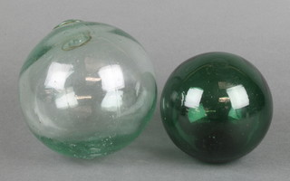 A clear glass fishing float 5" and a green ditto 4" 