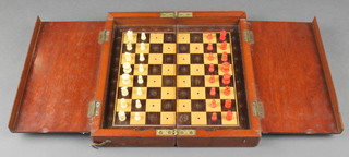 A 19th Century red and white stained carved ivory travelling chess set contained in a mahogany folding case 