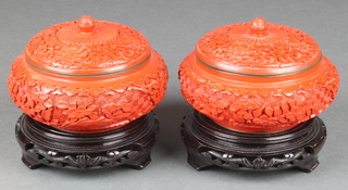Two Chinese cinnabar style lacquered jars and covers, raised on pierced hardwood bases 3"  