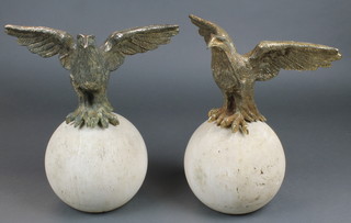 A pair of gilt metal figures of eagles with outstretched wings, raised on circular turned stone bases 13" 