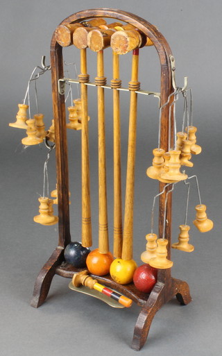 A table top croquet set comprising 4 turned mallets, 10 hoops, 4 coloured balls, stick marker (damaged), raised on a bent oak stand
