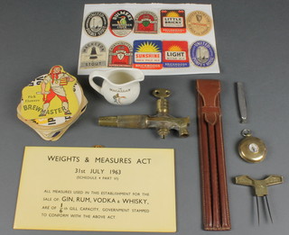 A gilt metal collapsible cup contained in a gilt metal case, the lid set a compass, a spigot with locking tap, a barrel measure and other items of brewery related interest 