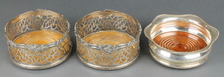 A pair of silver plated pierced coasters and one other