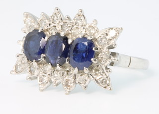 An 18ct white gold sapphire and diamond ring, the 3 oval sapphires surrounded by 24 brilliant cut diamonds, size Q