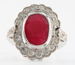 A 14k White gold oval cut ruby (approx 4.5ct) and 16 stone diamond ring with two diamonds to each shoulder Size O