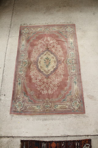 A peach ground and floral patterned Chinese carpet 109" x 71", slight stain