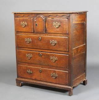 An 18th Century East Anglian oak chest, the moulded top above an arched panelled door flanked by 2 deep drawers with 3 long drawers, raised on bracket feet, having brass pierced back plates and swing handles and oval escutcheons 37"h x 32"w x 19"d 