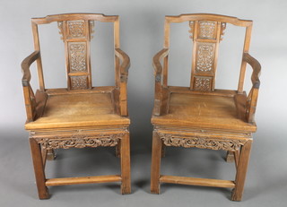 A pair of mid 20th Century Chinese Padouk wood armchairs, the pierced back with stylised dragon heads and flowers with solid seats, raised on straight legs 