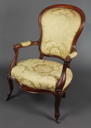A Victorian mahogany show frame open arm chair upholstered in yellow material raised on cabriole supports 