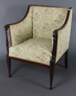 An Edwardian inlaid mahogany armchair, the seat and back upholstered in green floral material, raised on square tapering supports 