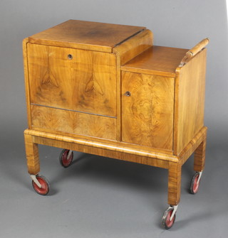 An Art Deco figured walnut cocktail cabinet trolley, the hinged lid with quarter veneered top revealing a fitted interior flanked by a cupboard and raised on square feet 29"h x 28"w x 14"d 