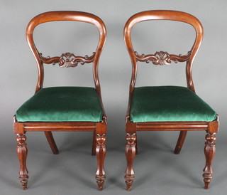 A pair of Victorian mahogany balloon back dining chairs with shaped mid rails and upholstered drop in seats, raised on chamfered supports 