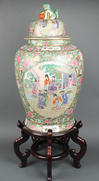 A 20th Century famille rose baluster vase and cover decorated with figures in pavilions on a ground of insects and flowers with lion finial 24" on a hardwood stand 