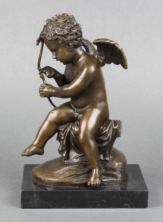 A bronze figure of a seated cupid, raised on a black marble base 8" 