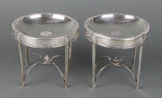 A pair of silver shallow dishes modelled as circular occasional tables, raised on square tapered supports and X framed stretchers, 1910, 4" 