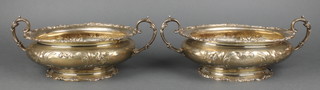 A pair of American sterling two handled dishes with scroll rims and fancy handles with repousse floral decoration 12 1/2" 1660gr