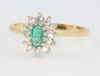 An 18ct yellow gold oval emerald and diamond cluster ring, size N