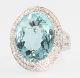 A 14ct white gold aquamarine and diamond cluster ring, the centre stone approx. 10.6ct surrounded by brilliant cut diamonds on an open shank approx. 1.1ct, size M