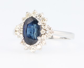 A 14ct white gold oval sapphire and brilliant cut diamond ring, the centre stone approx. 2.5ct surrounded by 0.5ct of diamonds, size P 1/2