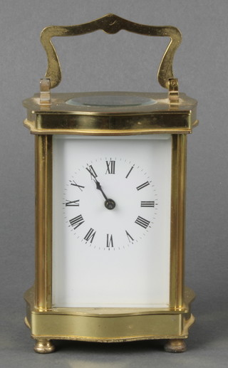 A carriage clock with enamelled dial and Roman numerals contained in a gilt metal serpentine shaped case, raised on turned feet 