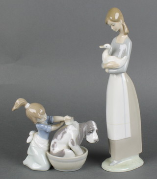 A Lladro figure group of a girl washing a dog 5455 5" and a Nao figure of a standing girl cradling a goose 11" 