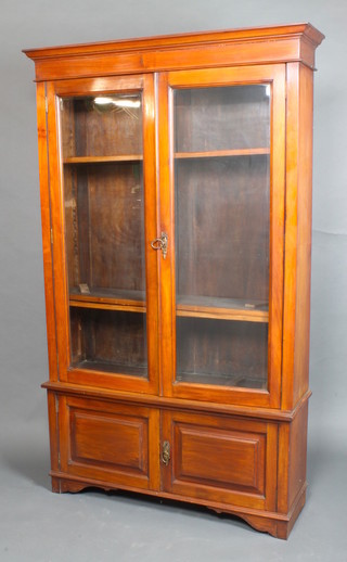 An Edwardian walnut bookcase on cabinet, the upper section with moulded cornice, fitted adjustable shelves enclosed by bevelled panelled glazed doors, the base fitted a cupboard, raised on bracket feet 78"h x 47"w x 13 1/2"d 