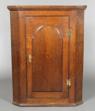 A Georgian oak hanging corner cabinet with moulded cornice, fitted shelves enclosed by arched panelled doors with H framed hinges 37"h x 28"w x 15 1/2"d 
