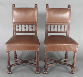 A pair of Victorian Italian carved walnut standard chairs with lion mask decoration, the seats and backs upholstered in rexine, with lion mask finials, bobbin turned finials and X framed stretcher, raised on turned and fluted supports