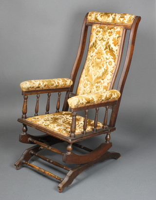 A 19th Century mahogany American rocking chair upholstered in sculpted Dralon with bobbin turned decoration 