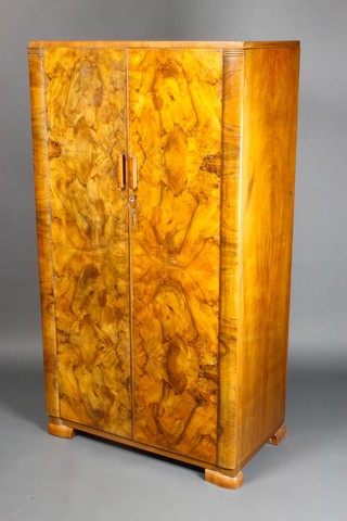 A gentleman's Art Deco figured walnut combination wardrobe enclosed by panelled doors, raised on bracket feet 59"h x 33"w x 18 1/2"d 
