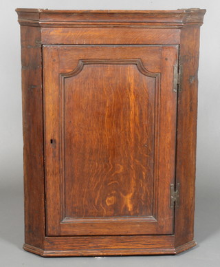An 18th Century oak hanging corner cabinet with moulded cornice enclosed by arched panelled doors with H framed hinges 31"h x 23"w x 12"d 