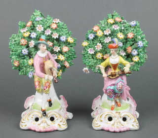 A pair of Samson Chelsea style figures of a pair of musicians seated beneath flowering trees with rococo bases 7" 