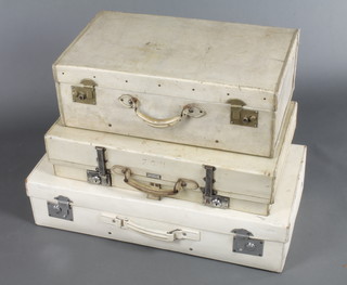 A white leather suitcase with chrome mounts 8"h x 16 1/2" x 23,  a Cresent parchment suitcase with chrome locks 6 1/2" x 28" x 16" and a parchment suitcase with brass locks 9" x 26" x 15"  