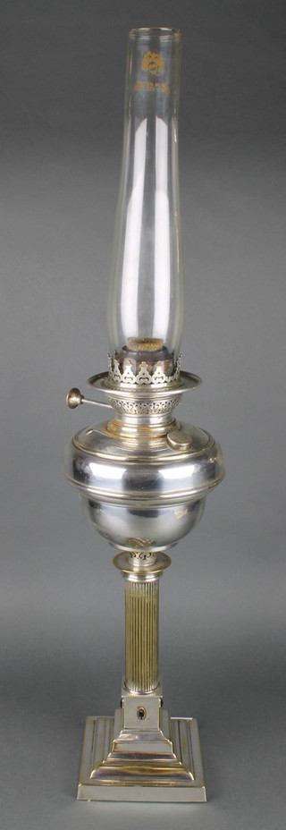 An oil lamp with silver plated reservoir raised on a reeded column and stepped base 