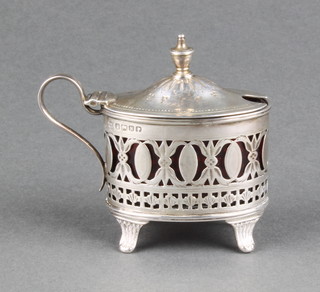 A Victorian silver oval mustard pot with pierced decoration on scroll feet with red glass liner, Sheffield 1880 