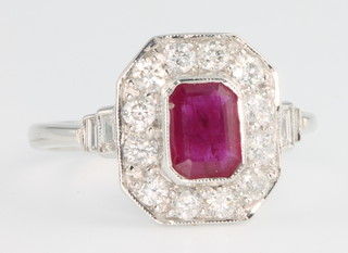 An 18ct white gold Art Deco style ruby and diamond cluster ring, the centre ruby approx. 0.8ct surrounded by brilliant cut diamonds and baguette diamonds to the shoulders, size P
