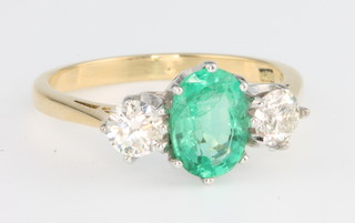 An 18ct yellow gold emerald (1) and diamond (2) stone ring, the centre stone approx. 1.1ct flanked by brilliant cut diamonds each 0.3ct, size M 1/2