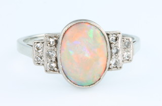 An 18ct white gold opal and diamond ring, the centre oval cut stone flanked by 5 brilliant cut diamonds, size L