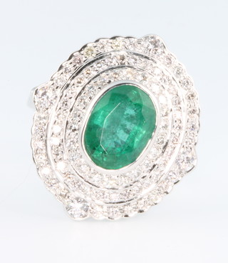 An 18ct white gold oval emerald and diamond dress ring, the centre stone approx 3.75ct surrounded by 3 tiers of brilliant cut diamonds 1.5ct, size Q, with certificate 