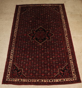 A red ground Iranian Husseinabad carpet with star shaped medallion to the centre and all-over geometric designs 127 1/2" x 82" 