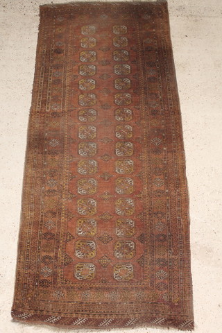 A tan ground Afghan runner with 30 octagons to the centre 106" x 43", some wear 