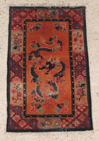 An orange ground Chinese rug, the centre decorated a dragon 34" x 22" (moth to centre) 