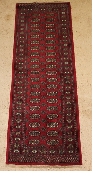 A red ground Bokhara runner with 40 octagons to the centre 97" x 32" 