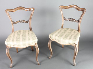 A pair of Victorian rosewood buckle back chairs with carved mid rails, the seats of serpentine outline raised on French cabriole supports 