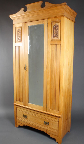 An Edwardian satinwood wardrobe with moulded cornice, enclosed by a bevelled plate mirror panelled door flanked by a pair of carved panels, the base fitted 1 long drawer 80"h x 40"w x 18"d 
