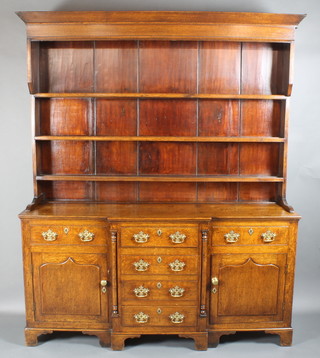 A Georgian oak dresser, the raised back with moulded cornice above 3 shelves, the break front base fitted 4 drawers with columns to the sides, flanked by 2 drawers above cupboards with arched panelled doors, having brass drop handles and raised on bracket feet, 84"h x 69"w x 20"d 